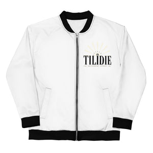 A white bomber jacket with black cuffs, neck-lining, and hem. On the left breast the words "Nopaune. Til I Die. The Independent Apparel Co." are printed. Being the words light rays can be seen.