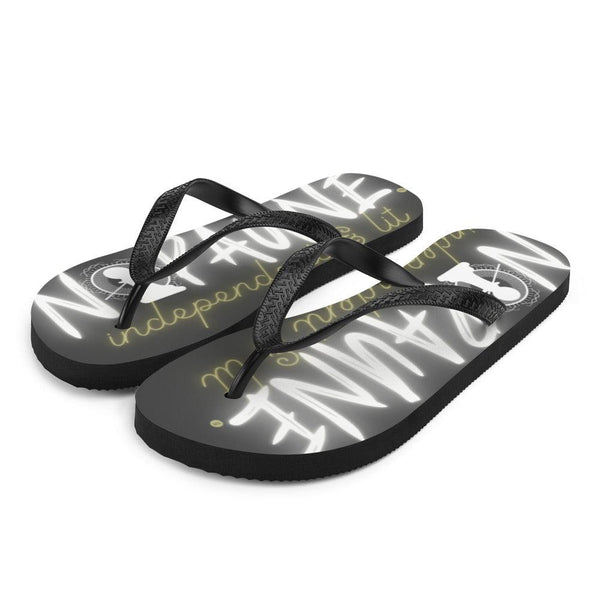Black flip-flops with black toe straps, facing the camera at an angle. The words "Nopaune. Independent & Lit" are printed on both flip-flops in white and yellow. The letter O in "Nopaune" has been replaced with the Nopaune logo (a chess pawn with a "not allowed sign" laid over it, surrounded by spokes/rays and broken infinity signs).